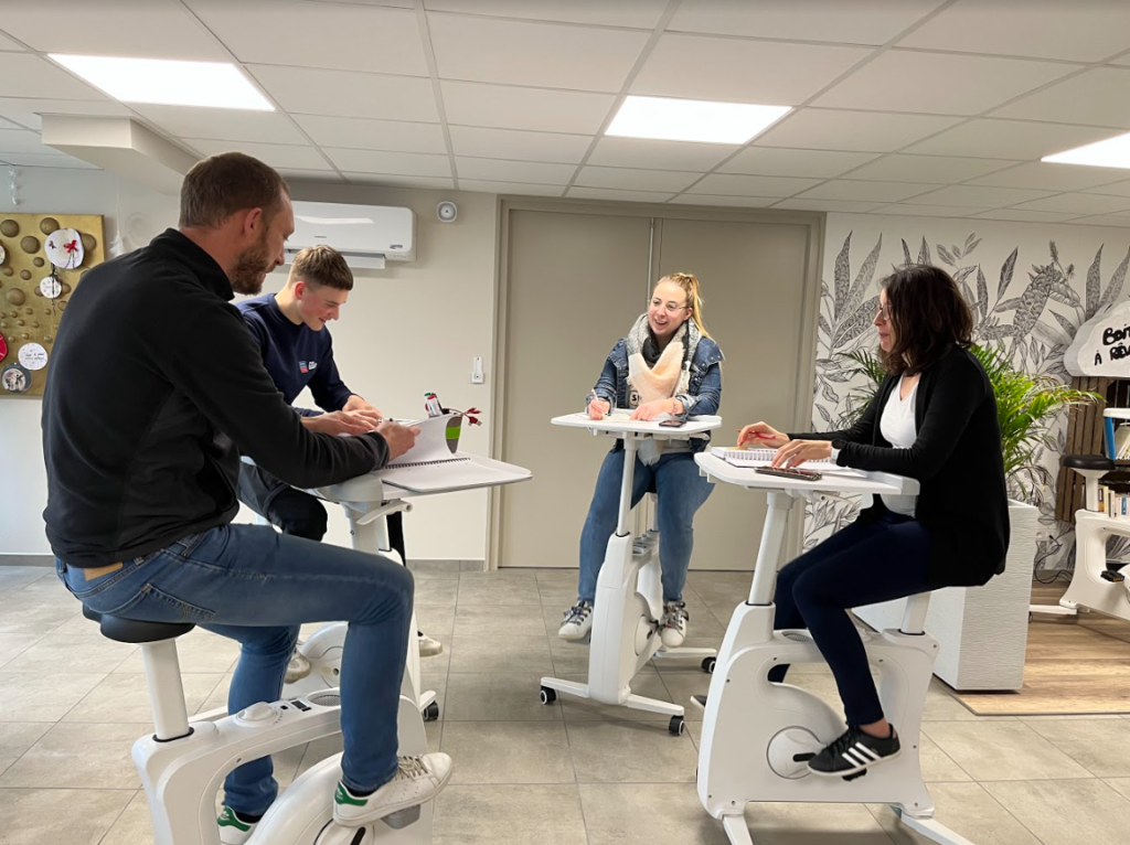 Réunion de collaborateurs souriants et joyeux sur des vélos bureaux. 